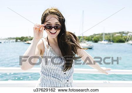 Stock Image - USA, Virgin Islands, Saint Thomas, Woman peeking over sunglasses. Fotosearch