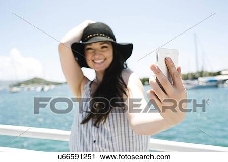 Stock Image - USA, Virgin Islands, Saint Thomas, Woman doing selfie with bay in background. Fotosearch