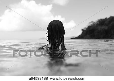 Stock Photo - USA, Virgin Islands, Saint Thomas, Woman with long hair standing in bay. Fotosearch