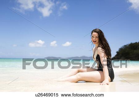 Stock Photography - USA, Virgin Islands, Saint Thomas, Beautiful woman sitting on shore. Fotosearch