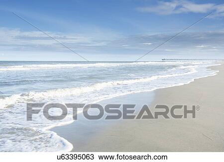 Stock Image - Waves splashing into sandy beach. Fotosearch