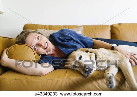Woman and Labrador Retriever lying down on sofa View Large Photo Image Stock Image - Woman and Labrador Retriever lying down on sofa. Fotosearch