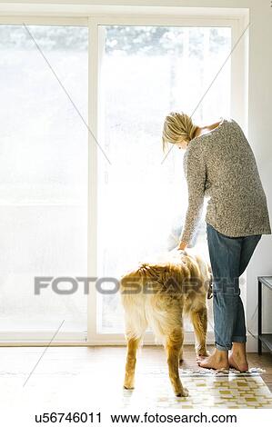 Stock Image - Woman at home with dog. Fotosearch