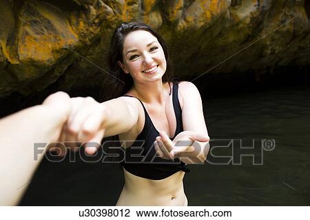 Woman by water holding person's hand and looking at camera View Large Photo Image Stock Image - Woman by water holding person's hand and looking at camera. Fotosearch