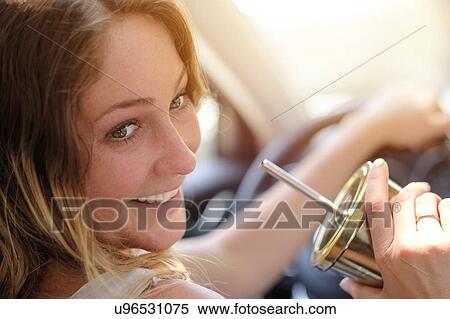 Woman driving and drinking from gold cup View Large Photo Image Stock Photography - Woman driving and drinking from gold cup. Fotosearch