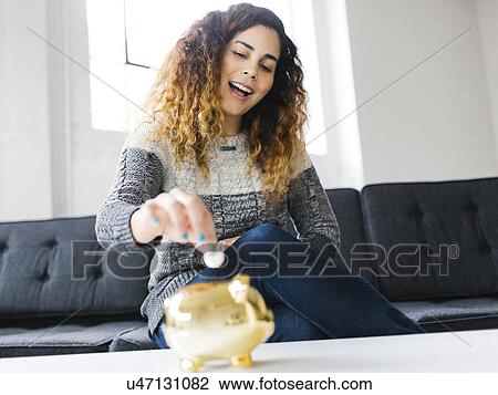 Woman dropping coin into gold piggy bank View Large Photo Image Stock Image - Woman dropping coin into gold piggy bank. Fotosearch