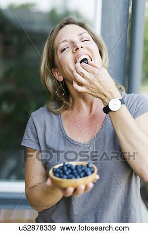 Stock Photo - Woman eating blueberries. Fotosearch