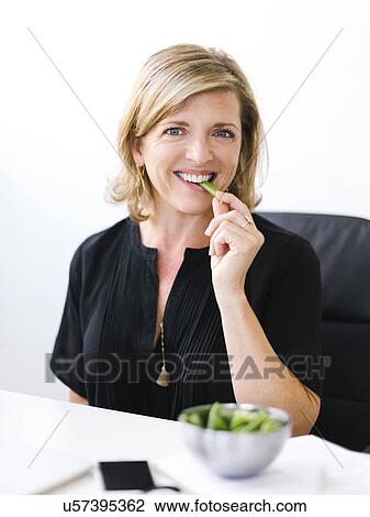 Stock Image - Woman eating green peas. Fotosearch