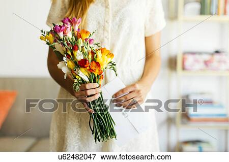 Stock Photo - Woman holding bouquet and letter. Fotosearch