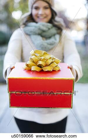 Stock Photograph - Woman holding Christmas gift. Fotosearch