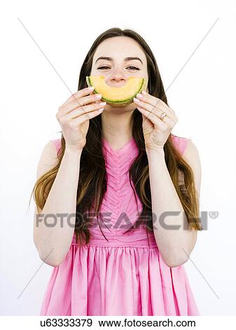 Stock Photo - Woman holding slice of melon in front of her mouth. Fotosearch