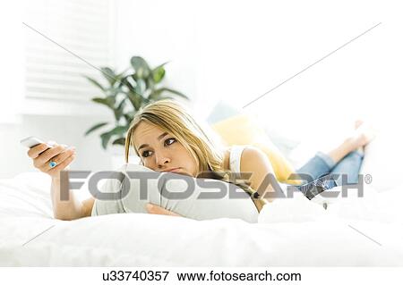 Woman in bed with tv remote View Large Photo Image Stock Photo - Woman in bed with tv remote. Fotosearch