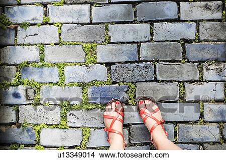 Picture - Woman in sandals standing on street. Fotosearch