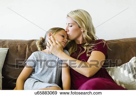Stock Photo - Woman kissing daughter (6-7) on forehead. Fotosearch