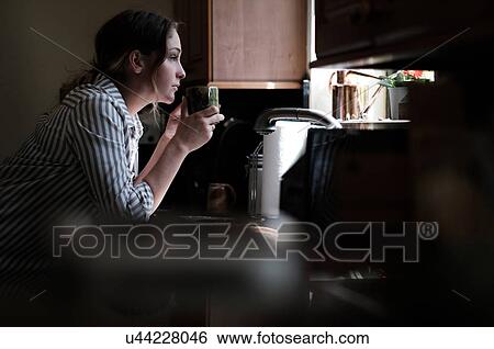 Stock Photograph - Woman looking through kitchen window. Fotosearch
