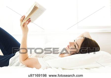 Woman lying on bed and reading book View Large Photo Image Stock Photo - Woman lying on bed and reading book. Fotosearch