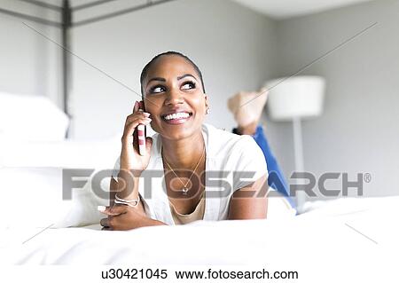 Woman lying on bed and using smart phone View Large Photo Image Stock Photography - Woman lying on bed and using smart phone. Fotosearch