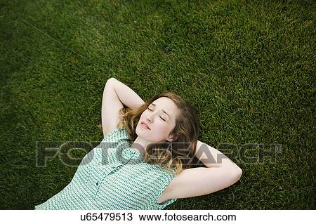 Stock Image - Woman lying on grass and sleeping. Fotosearch
