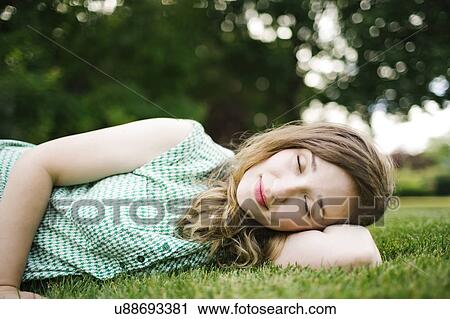 Stock Image - Woman lying on grass and sleeping. Fotosearch
