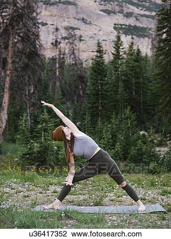 Stock Image - Woman practicing yoga in forest. Fotosearch