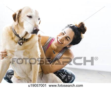 Stock Image - Woman practicing yoga with dog. Fotosearch