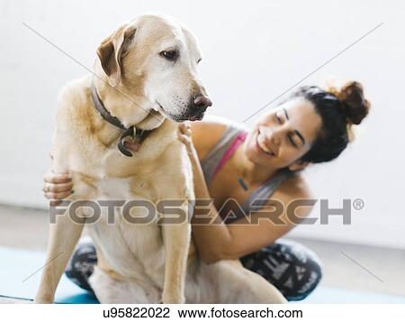 Stock Image - Woman practicing yoga with dog. Fotosearch