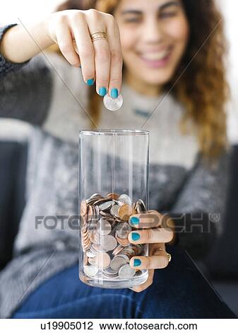 Stock Image - Woman putting coin into glass. Fotosearch