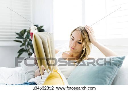 Woman reading book on sofa View Large Photo Image Stock Image - Woman reading book on sofa. Fotosearch