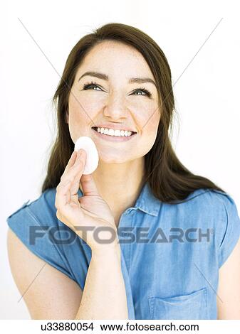 Picture - Woman removing make-up with cotton pad. Fotosearch
