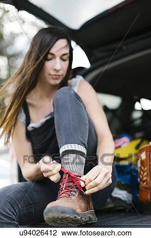 Woman sitting in car trunk and tying hiking shoes View Large Photo Image Stock Image - Woman sitting in car trunk and tying hiking shoes. Fotosearch