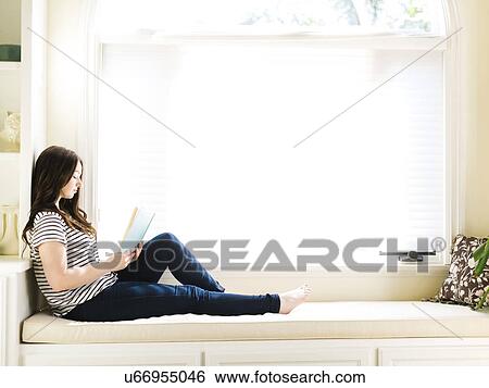 Woman sitting on couch with book in hands View Large Photo Image Stock Photograph - Woman sitting on couch with book in hands. Fotosearch