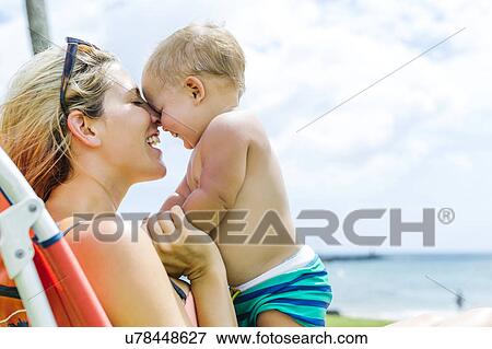Stock Photo - Woman sitting on deck chair with little son (18-23 months). Fotosearch