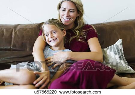 Stock Image - Woman sitting with daughter (6-7) on couch. Fotosearch