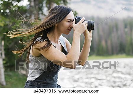 Stock Photography - Woman taking pictures by lake. Fotosearch