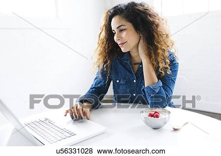 Woman using laptop at table View Large Photo Image Stock Photo - Woman using laptop at table. Fotosearch