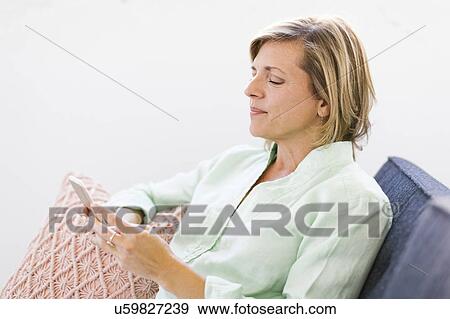 Woman using smart phone on sofa View Large Photo Image Stock Photo - Woman using smart phone on sofa. Fotosearch