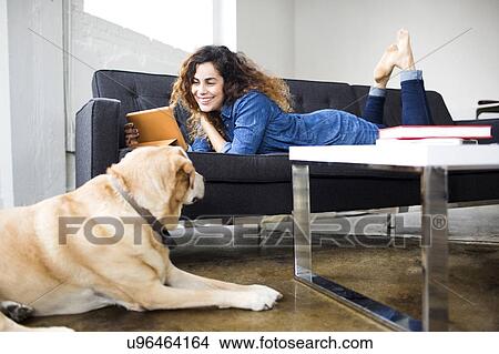 Picture - Woman watching tablet on sofa. Fotosearch