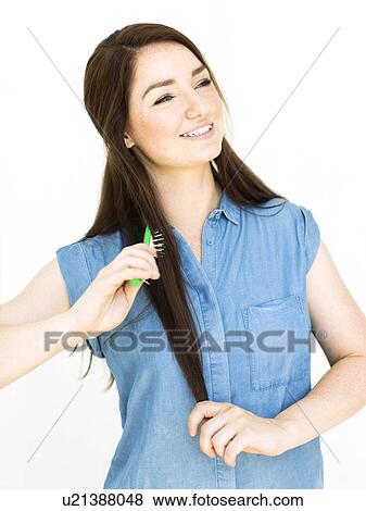 Stock Photo - Woman wearing blue top brushing hair. Fotosearch