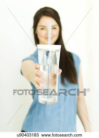 Woman wearing blue top holding drinking glass View Large Photo Image Stock Image - Woman wearing blue top holding drinking glass. Fotosearch