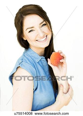 Stock Photo - Woman wearing blue top holding peach. Fotosearch
