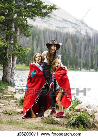 Stock Image - Woman with son (6-7) and daughter (8-9) standing by lake. Fotosearch