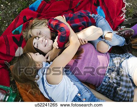 Stock Photography - Woman with son (6-7) and daughter (8-9) lying on blanket. Fotosearch