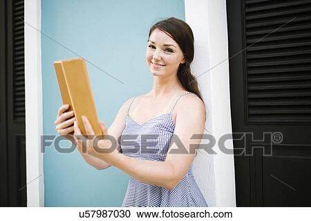 Stock Image - Woman with tablet doing selfie on city street. Fotosearch