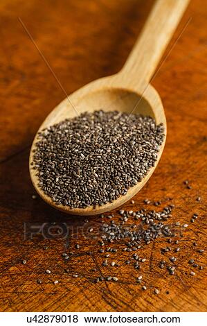 Stock Photo - Wooden spoon full of chia seeds on table. Fotosearch