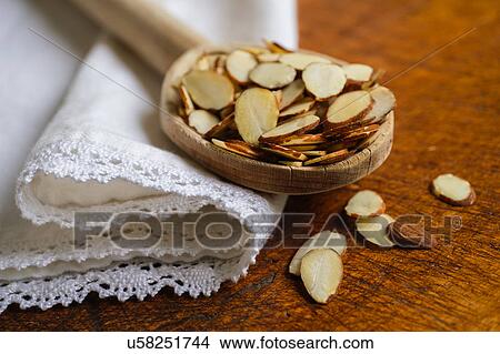 Picture - Wooden spoon full of sliced almond on table. Fotosearch