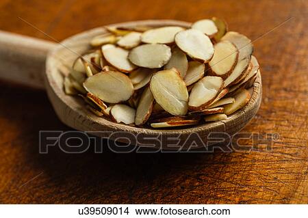 Picture - Wooden spoon full of sliced almonds on table. Fotosearch