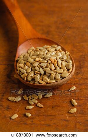 Stock Image - Wooden spoon full of sunflower seeds on table. Fotosearch