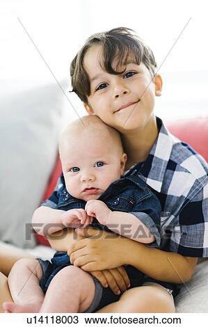 Stock Image - Young boy (6-7) holding brother (2-5 months). Fotosearch