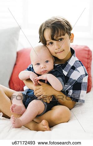 Stock Image - Young boy (6-7) holding brother (2-5 months). Fotosearch