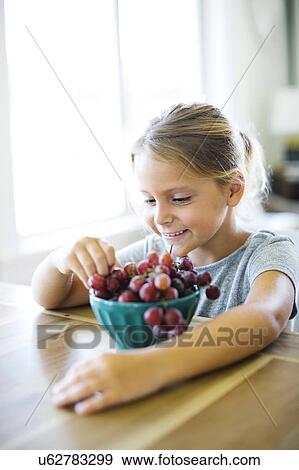 Stock Photo - Young girl (6-7) eating fresh grapes. Fotosearch